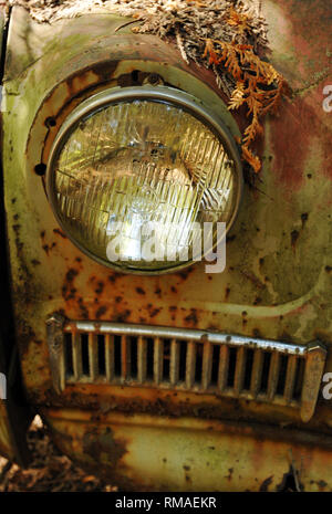 Détail du projecteur sur une voiture classique de rouille abandonné dans un parc à ferrailles. Banque D'Images