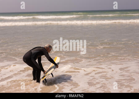 Senior male surfer avec une planche de surf surf en mer Banque D'Images