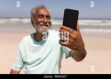Selfies Senior man talking with mobile phone on beach Banque D'Images