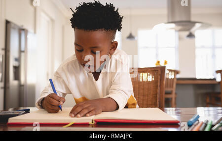 Cute African American boy doing homework at table Banque D'Images