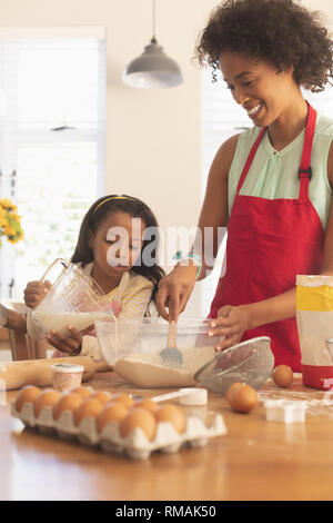 African American mother and daughter mélanger tous les ingrédients de la pâte à biscuits dans la cuisine Banque D'Images