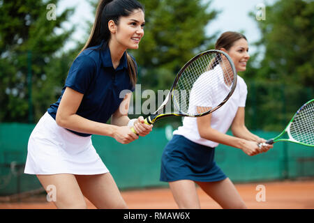 Les jeunes femmes happy fit jouer au tennis sur le court de tennis Banque D'Images