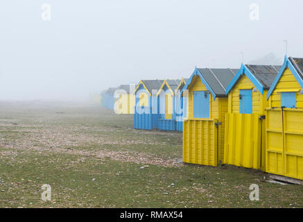 Cabines de plage dans des conditions de brouillard brumeux sur une plage déserte en hiver sur une plage au Royaume-Uni. Banque D'Images