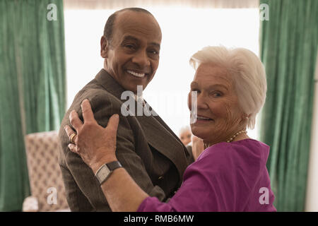 Vue latérale d'happy senior couple looking at camera while dancing Banque D'Images