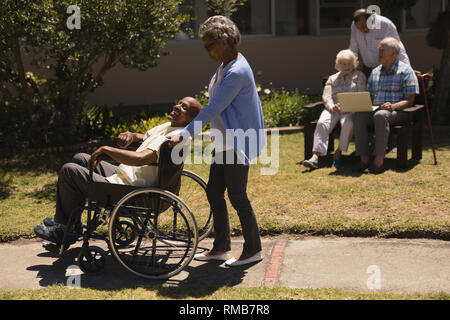 Vue avant du senior woman poussant senior man in a wheelchair Banque D'Images