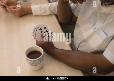 Senior man playing cards dans la salle de séjour Banque D'Images