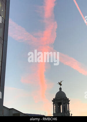 Les traînées de vapeur d'aéronefs forment une Saint-valentin 'Kiss' dans le ciel au-dessus de Londres, au-dessus de la statue de ballerine russe Anna Pavlova sur le toit du Victoria Palace Theatre. Banque D'Images