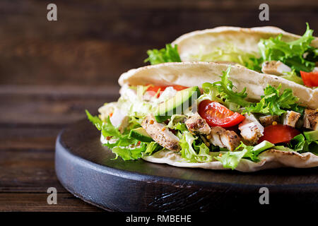 Pain pita grillé sandwiches avec la viande de poulet, avocat, tomate, concombre et la laitue servi sur fond de bois. Close up. Fast food saine conce Banque D'Images