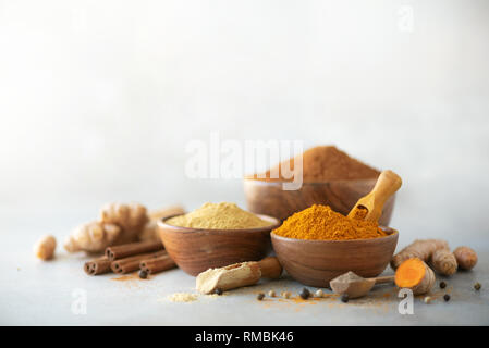 Ingrédients pour le curcuma latte. Rez-de curcuma, racine de curcuma, cannelle, gingembre, poivre noir sur fond gris. Épices pour le traitement d'Ayurvedic. Alte Banque D'Images