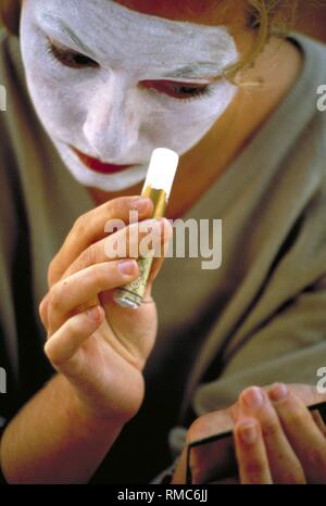 Un homme s'applique peinture blanche sur son visage. Banque D'Images