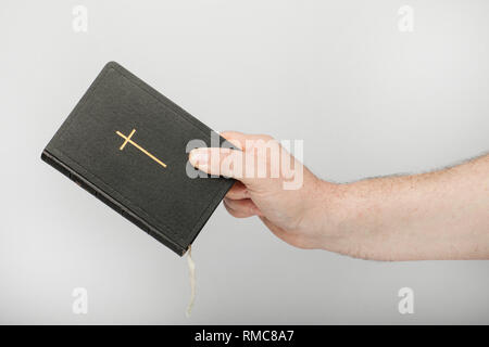 La main des hommes est titulaire d'une vieille Bible avec crucifix, isolé sur le fond blanc. Banque D'Images