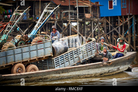 Lac Tonlé Sap, au Cambodge. 20 Décembre, 2017. Un groupe d'hommes ride cours des maisons sur pilotis sur le lac Tonlé Sap dans un grand bateau en bois transportant des tracteurs et de w Banque D'Images