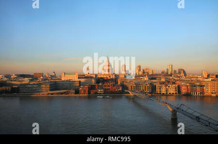 Vue du coucher de la Cathédrale St Paul et Millennium Bridge vu de la Tate Modern. De couleur orange spectaculaire coucher du soleil présent sur le ciel bleu. Banque D'Images