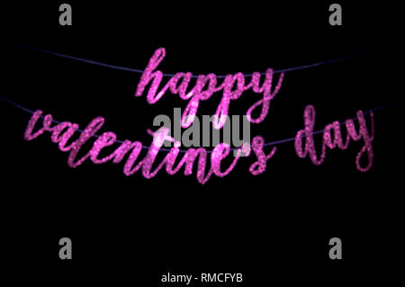 Flou artistique romantique Happy Valentine's Day Message en rose manuscrites mousseux pendaison bannière script sur un fond noir foncé Banque D'Images