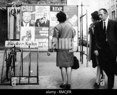 Une femme en face d'affiches électorales pour l'élection fédérale de 1969. Le SPD annonce avec son candidat de chancelier Willy Brandt et le slogan 'So que vous pouvez vivre en paix demain aussi', le FDP annonce avec 'nous abandonner les traditions archaïques," l' partie annonce avec ' la nouvelle voie". Banque D'Images