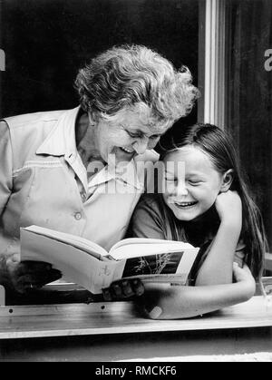 Une vieille femme avec sa petite-fille en train de lire un livre. Banque D'Images