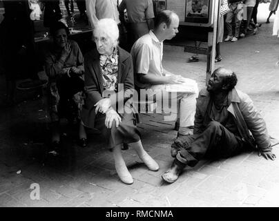 Un vieux mendiant estropié, à Johannesburg pose une femme blanche pour l'aumône. Banque D'Images