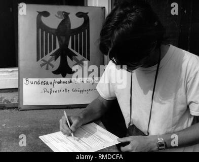 Un jeune homme, qui a fui par la Hongrie de la RDA, remplit une demande d'admission dans le camp de réfugiés de Schoeppingen. Banque D'Images