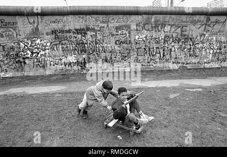 Enfants jouant sur le mur de Berlin dans la Zimmerstrasse dans le quartier Kreuzberg. Banque D'Images