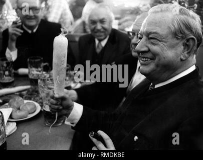 Le premier ministre bavarois Alfons Goppel est titulaire d'un radis à la fête dans sa main. Banque D'Images