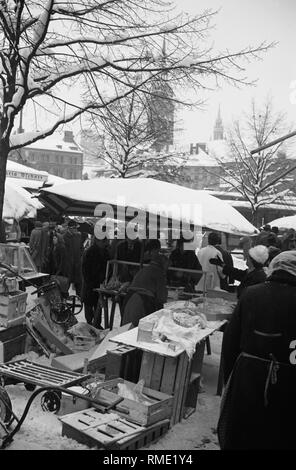 Stand au marché Viktualienmarkt de Munich dans l'hiver de 1962. Dans l'arrière-plan les tours d'église de Saint Pierre et de l'Esprit Saint (l'Église Heiliggeistkirche). Banque D'Images