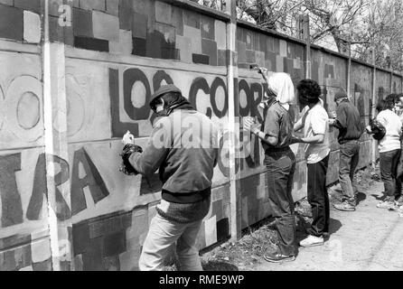 Les membres masqués de la brigade de la jeunesse communiste 'Ramona Parra' peindre les murs avec des slogans lors d'un rassemblement de l'opposition au Chili. Banque D'Images