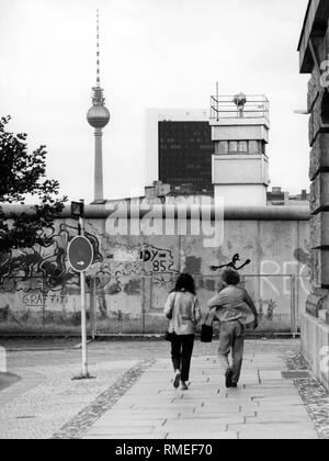 Un couple se dirige vers le mur de Berlin. Derrière le mur, l'image montre une vigie du GDR patrouille frontalière et la Tour de Télévision de Berlin. Mur de Berlin de 1980 jusqu'à octobre 1989, l'Allemagne, Banque D'Images