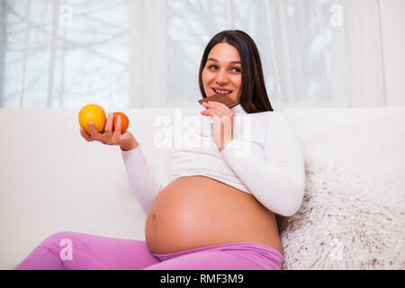 Femme enceinte aime manger les bonbons et les fruits frais. Banque D'Images