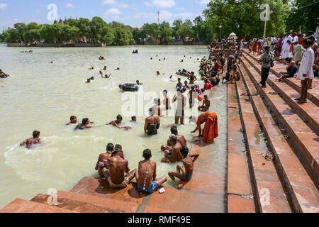 L'Inde, Rajasthan, Kolayat, 08/24/2006 : Le lac artificiel de certaines personnes à Kolayat assis sur les gaths de la rive et d'autres prendre un bain Banque D'Images