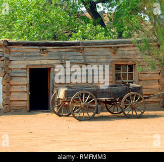 En bois ancien wagon est garé sur une voie poussiéreux à l'extérieur d'une cabane en rondins. Échelle en bois s'appuie contre le bâtiment. Banque D'Images