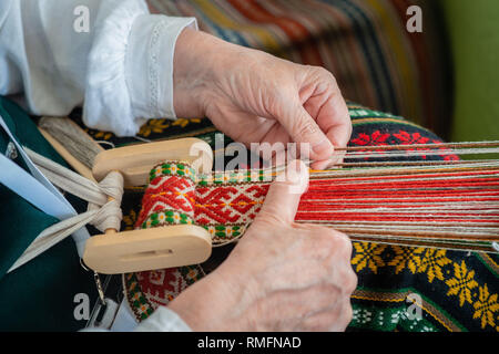 Femme travaillant à la tisser. Artisanat ethnique traditionnel de Baltique. - Image Banque D'Images