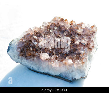 Améthyste cristal naturel cluster avec inclusions de goethite du Brésil sur la neige blanche à un jour d'hiver ensoleillé. Banque D'Images