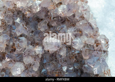 Améthyste cristal naturel cluster avec inclusions de goethite du Brésil sur la neige blanche à un jour d'hiver ensoleillé. Banque D'Images