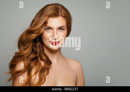 Femme aux cheveux rouge parfait. Jeune fille rousse élégante avec curly hairstyle. Smiling woman portrait Banque D'Images