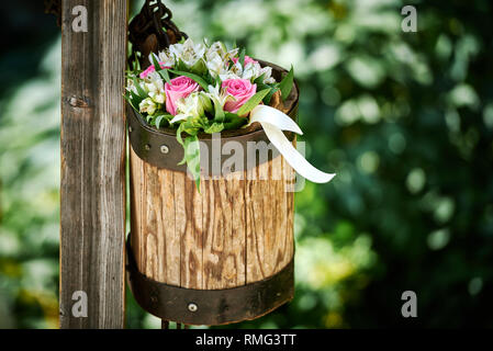 Bouquet de jolies fleurs en pot en bois miteux sur perche sur fond flou de jardin Banque D'Images