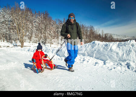 Heureux père et son fils bénéficiant de traîneau ride. Famille heureuse à traineau en hiver avoir du plaisir ensemble. Sortie rapide. Sous la conduite de la famille hiver traîneau Banque D'Images