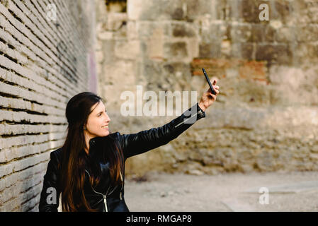 Happy young woman making millénaire autoportraits à elle-même, tout en rêvant de flirter avec le garçon qu'elle est amoureuse de lors du téléchargement des photos à la Banque D'Images