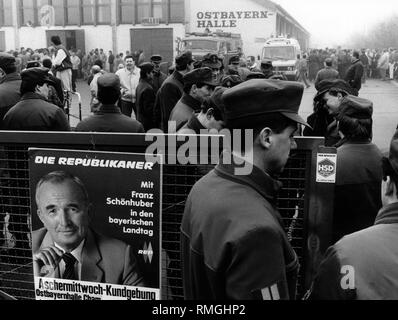 Cette photo montre l'attente des gens et les policiers en face de l'Ostbayernhalle Cham, où a lieu un événement de l'élection des Républicains pour l'élection fédérale en Bavière, à laquelle le chef du parti Franz Schoenhuber prononce un discours. Schoenhuber se vante d'avoir plus d'auditeurs que le CSU à leurs élections à Passau. Dans le premier plan, une affiche annonce ce mercredi des Cendres Rassemblement des républicains avec leur président Franz Schoenhuber. Banque D'Images