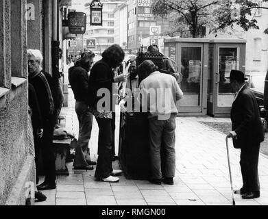 Les jeunes sont debout devant leur propre maison bar sur Occamstrasse dans le quartier de Schwabing à Munich, sur laquelle sont placés les bougies. Un vieux passant examine de plus près ce qui se passe. Banque D'Images