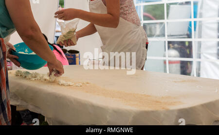 Strudel aux pommes fait maison pâte sur une nappe de lin traditionnel prêt pour faire le fromage cottage pie et autres pâtisseries. Les femmes rouler la pâte avec cirée Banque D'Images