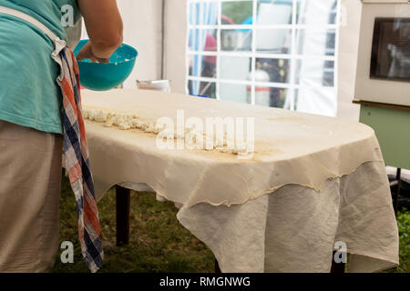 Strudel aux pommes fait maison pâte sur une nappe de lin traditionnel prêt pour faire le fromage cottage pie et autres pâtisseries. Les femmes rouler la pâte avec cirée Banque D'Images