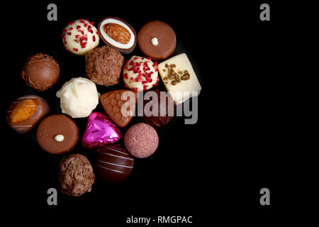 Gros plan d'une sélection de chocolats de luxe, avec un coeur rose enveloppé d'aluminium, ce qui pourrait être pour la Saint-Valentin, un anniversaire ou Noël. Banque D'Images