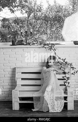 Belle jeune femme parisienne en robe de soie blanche longtemps assis sur le banc de la journée d'été. Banque D'Images