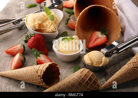 Cuillère à crème glacée à la vanille avec des fraises fraîches et des cônes de glace sur un fond rustique Banque D'Images