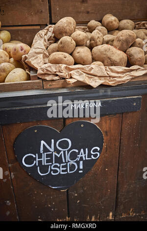 Différentes variétés de pommes de terre biologiques en vente sur un étal dans un marché fermier local. Le format Portrait. Banque D'Images