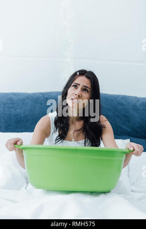 Contrarié brunette girl holding green bassin en double et la recherche de Banque D'Images