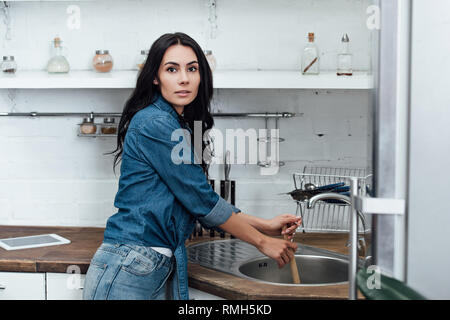 Femme heureuse en utilisant le poussoir dans l'évier de cuisine à