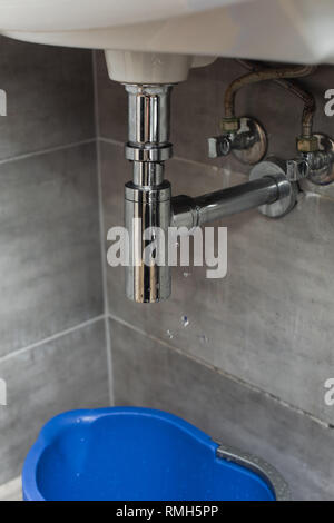 Seau bleu debout dans une salle de bains privative sous tuyau qui fuit Banque D'Images