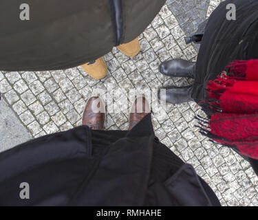 Vue d'en haut des jambes des gens parler. Ils se tiennent sur un trottoir pavé Banque D'Images