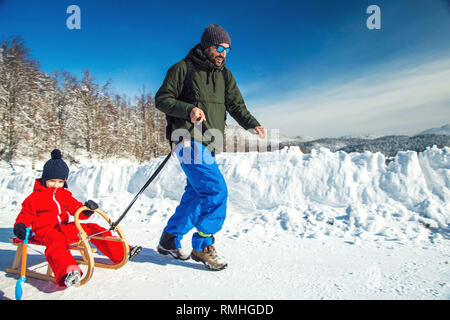 Heureux père et son fils bénéficiant de traîneau ride. Famille heureuse à traineau en hiver avoir du plaisir ensemble. Sortie rapide. Sous la conduite de la famille hiver traîneau Banque D'Images